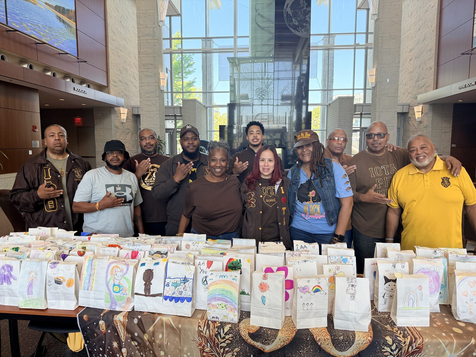 Brothers and Iota Sweethearts preparing decorated care bags at a community service event