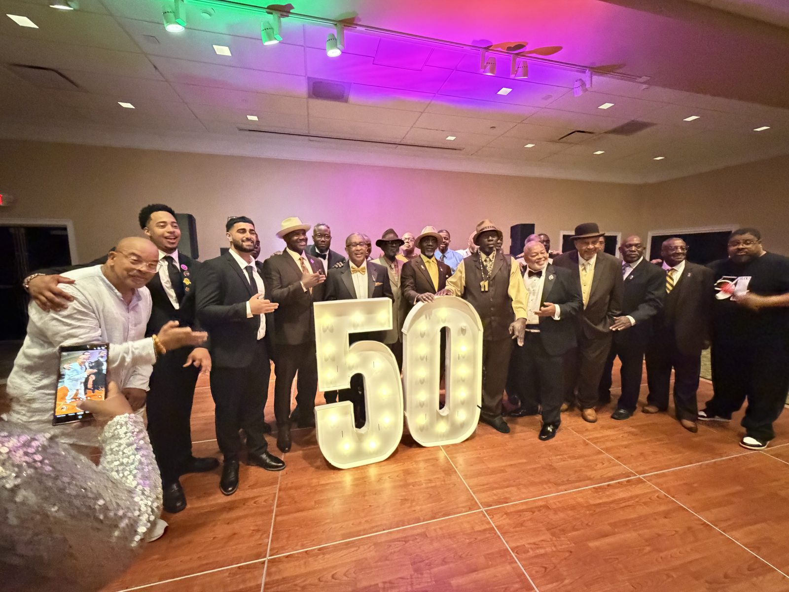 Men of Iota beside the lighted 50 at a formal celebration