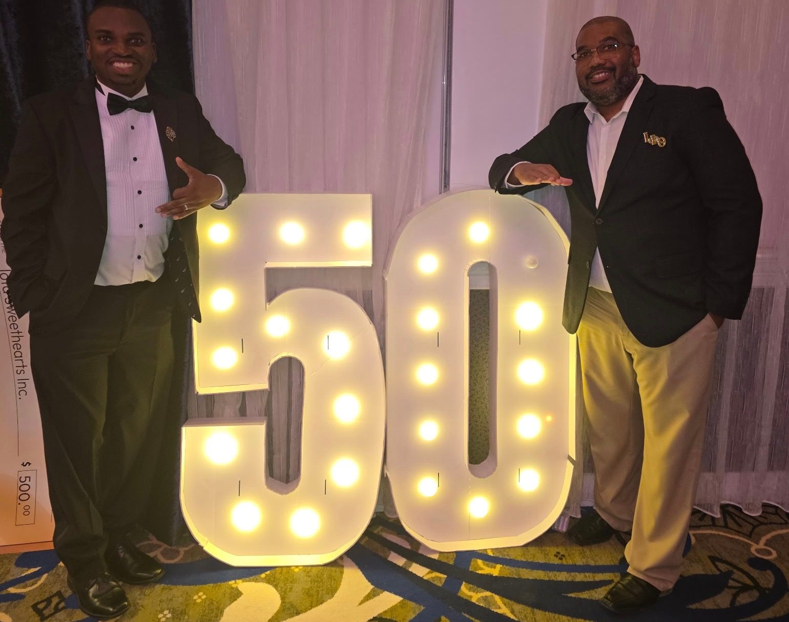 Two brothers beside the lighted anniversary numbers