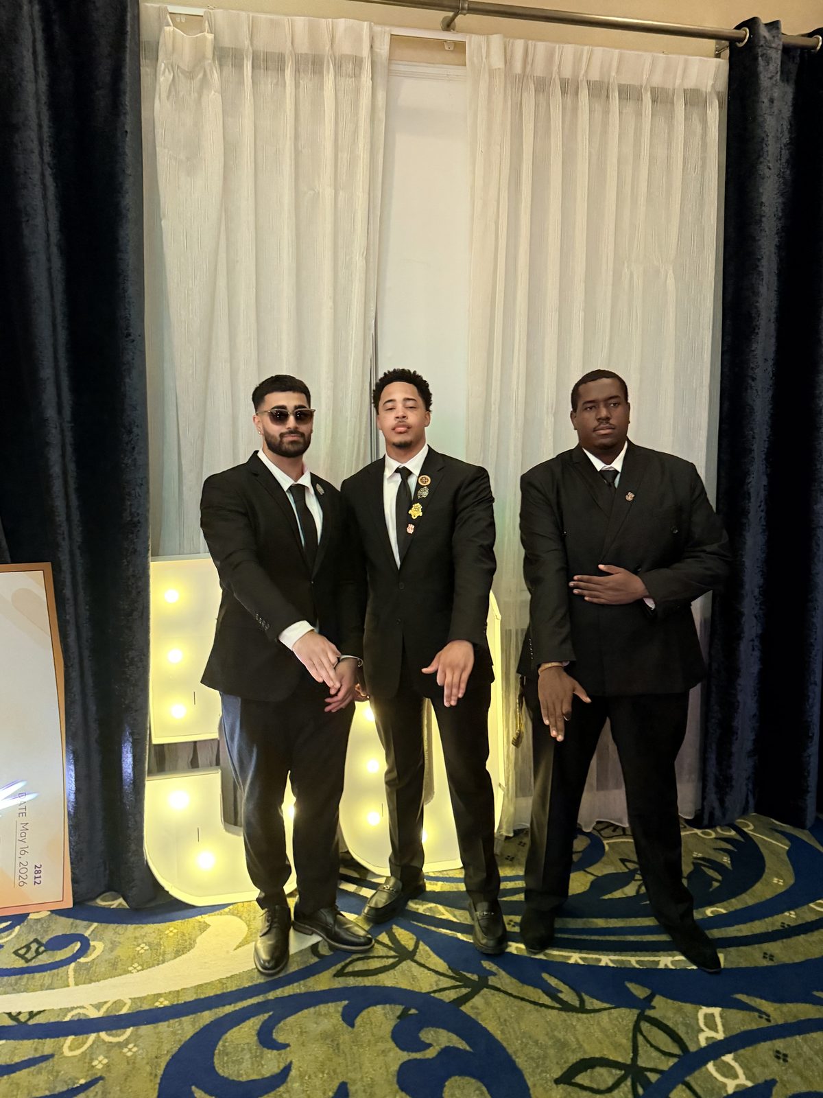 Three young brothers in dark suits at a gala